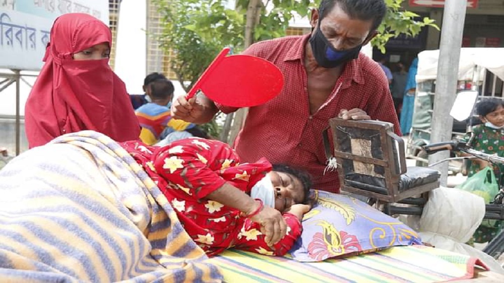 ছয় দিন ধরে জ্বরে ভুগছেন রাজশাহীর গোদাগাড়ীর হানুফা বেগম (৫০)। এরই মধ্যে শ্বাসকষ্ট বেড়ে গেলে তাঁকে রাজশাহী মেডিকেল কলেজ হাসপাতালে ভর্তির জন্য আনা হয়। পাশে দাঁড়িয়ে তাঁকে বাতাস করছেন স্বামী আবদুর রাজ্জাক- ছবি সংগৃহীত